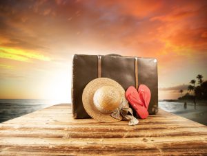 Concept of summer travelling with old suitcase and accessories. Blur beach on background